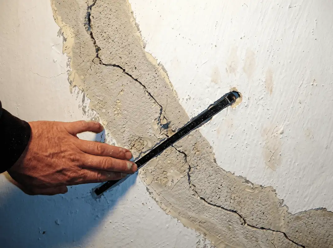 A wall with a large crack is being inspected by a professional in Fort Lauderdale, FL